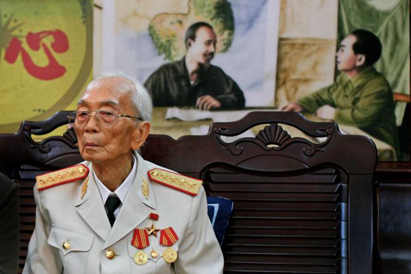 Gen. Vo Nguyen Giap stands in front of a painting of himself and Vietnamese President Ho Chi Minh